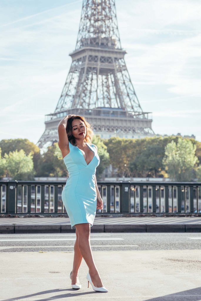 Portrait of instagram influencer in a blue dress in front of the Eiffel Tower in Paris